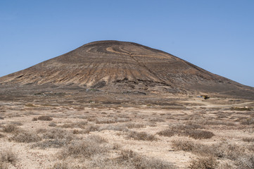 Lanzarote, Isole Canarie: strada sterrata, cespugli e paesaggio desertico con la Montagna Pedro Barba, il vulcano dell'isola La Graciosa