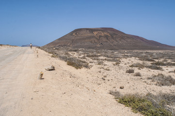 Lanzarote, Isole Canarie: strada sterrata, cespugli e paesaggio desertico con la Montagna Pedro Barba, il vulcano dell'isola La Graciosa