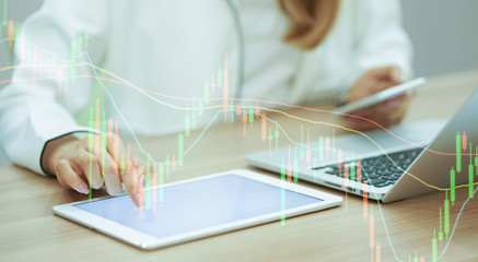 close up trader man hand swipe on tablet with stock graph dashboard and holding smartphone for check news at desk , multitasking people concept
