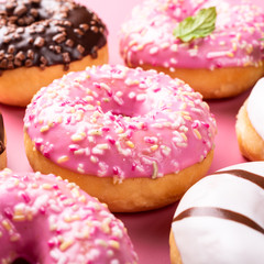 Colorful donuts on pink background with mint. Birthday party food concept with copy space.