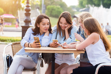 Young happy student girls are using smartphones in the Park.