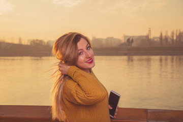 Beautiful woman posing outdoors and holding cellphone.