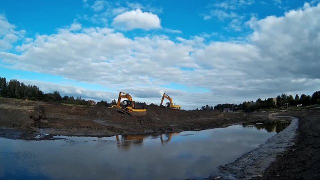 Excavators are working with Buckets to Clear Mud Sludge and Debris from the Bottom of the Drained River. Time lapse