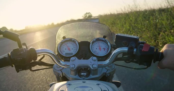 POV of a motorcyclist riding his motorbike along a road at sunset. Concept of: travel, transport, road, freedom and relaxation.