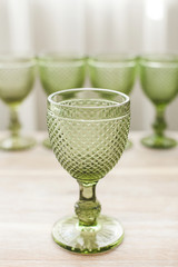 Empty glasses for drinks stand on a wooden white background. Colors are green.