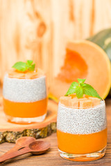 Chia pudding with pumpkin puree in beautiful glasses with green mint leaves and fresh ripe vegetable.
