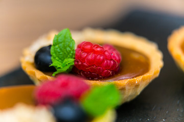 Homemade shortbread tartlets with custard cream and fruit..Tartlets dessert, pastry cakes with fresh fruit on wooden background
