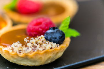 Homemade shortbread tartlets with custard cream and fruit..Tartlets dessert, pastry cakes with fresh fruit on wooden background