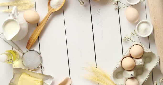 From above shot of various cooking tools and fresh pastry ingredients forming nice border on white timber tabletop