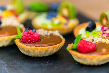 Homemade shortbread tartlets with custard cream and fruit..Tartlets dessert, pastry cakes with fresh fruit on wooden background