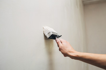 Hand Painting Wall With Copy Space. Brush with white paint in man's arm