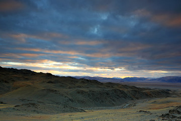 Landscape of highland steppe with mountains cloudy dramatic blue sky in beautiful sunrise at Bayan-Ulgii, Mongolia