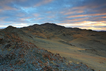 Landscape of highland steppe with mountains cloudy dramatic blue sky in beautiful sunrise at Bayan-Ulgii, Mongolia