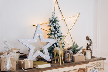 winter still life with Christmas decorations toy deer, star and gift boxes on light background. soft focus, blurred background