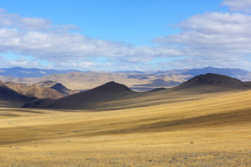 Fototapeta na wymiar Landscape of winding dirt road through rolling hills of Western Mongolian steppe