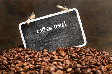 Café en granos junto a un cartel de pizarra negra con palabra escrita Coffee time. Vista de frente...