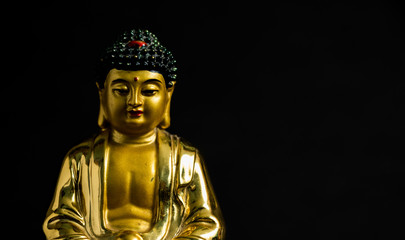 close up of Meditating Golden Buddha statue on black background