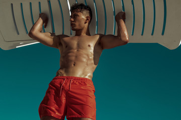 Strong face muscle male model in the open  summer shower on the vacation pool background with blue...