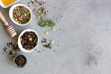 Black and green dried tea, mint leaves and honey on grey concrete background. Top view, copy space.