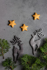 Traditional Christmas gingerbread cookies and juniper branch with Christmas decor on grey concrete background. Copy space for text.