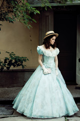 Fototapeta premium beautiful girl in historical dress, gloves, with a book in her hands in the park