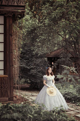 Fototapeta premium beautiful girl in historical dress, gloves, with a hat in her hands in the park