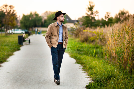 Handsome elegant man in the park wear jacket and fedora hat.