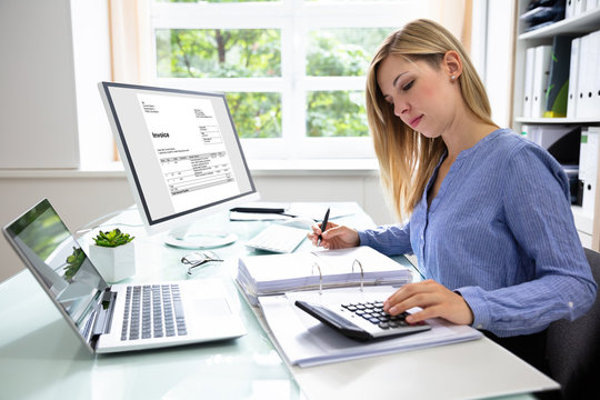 Young Businesswoman Calculating Bill In Office