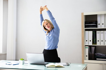 Businesswoman Stretching Her Arms At Workplace