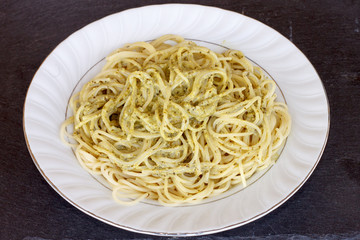 A plete of spaghetti with pesto sauce