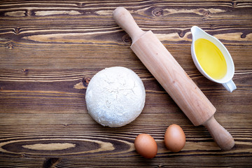Raw pizza dough and rolling pin on wooden background