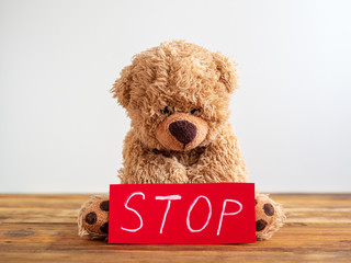 Kindesmissbrauch, Teddybär mit einem roten Stopschild auf einem Holzboden