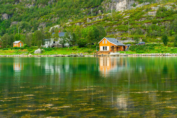 Obraz premium Typical Norwegian wooden huts in Ersfjordbotn village on the coast of Ersfjorden - beautiful fjord in Troms County, Norway