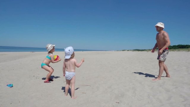 American father enjoying playing ball with young little kid on beach. Family Summer Beach Vacation. Slow Motion.