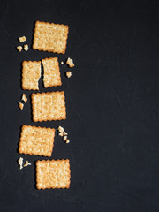 French cracker with sesame seeds on a black background. Flat lay, top view, copy space