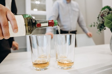 men pour drink whiskey together inside room