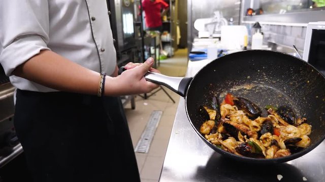 Chef presenting a pan with cooked seafood in resturant kitchen