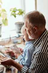Grandfather and grandson sitting at couch and watch family album