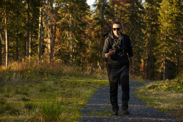 Female hiker in the forest looking on gps navigator. Finding right position.
