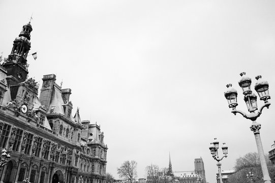 Paris, France. Hotel de ville (city hall) covered with snow in rare snowy morning in winter and Notre Dame cathedral at background. Black and white photo.