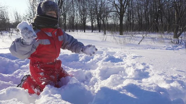 funny kid playing with snowballs on winter park