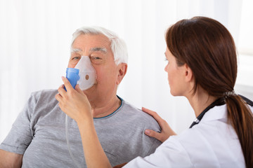 Doctor Holding Oxygen Mask Over Man's Face