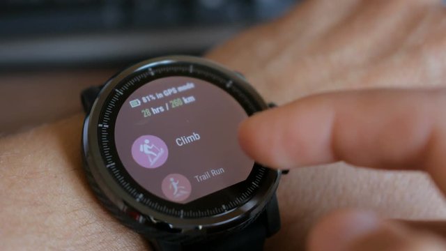 Young man making gestures on a wearable smart watch computer device, smartwatch closeup. Man using her smartwatch touchscreen wearable technology device.