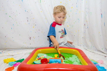 children play in an inflatable pool with kinetic sand