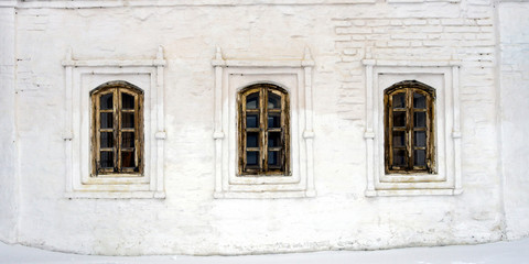 three old Windows in wooden frames in a stone white wall