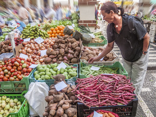 young woman buying organic fruit and vegetables on a farmers market in Funchal, Madeira,Portugal