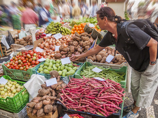 young woman buying organic fruit and vegetables on a farmers market in Funchal, Madeira,Portugal
