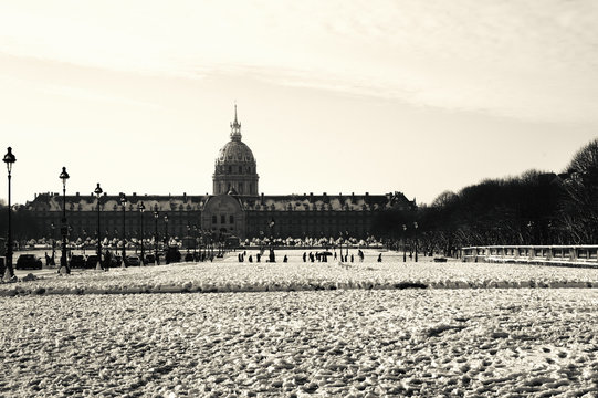 Fototapeta Paris under snow. Hotel national des Invalides and snow-covered lawn at foreground. View from Alexandre III Bridge. Black and white photo.