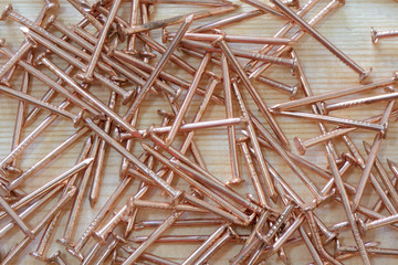 Small copper nails on wooden background