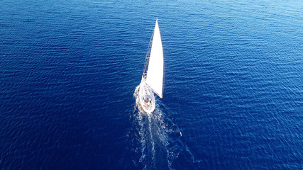 Aerial drone birds eye view of sail boat cruising in the deep blue Aegean sea, Greece